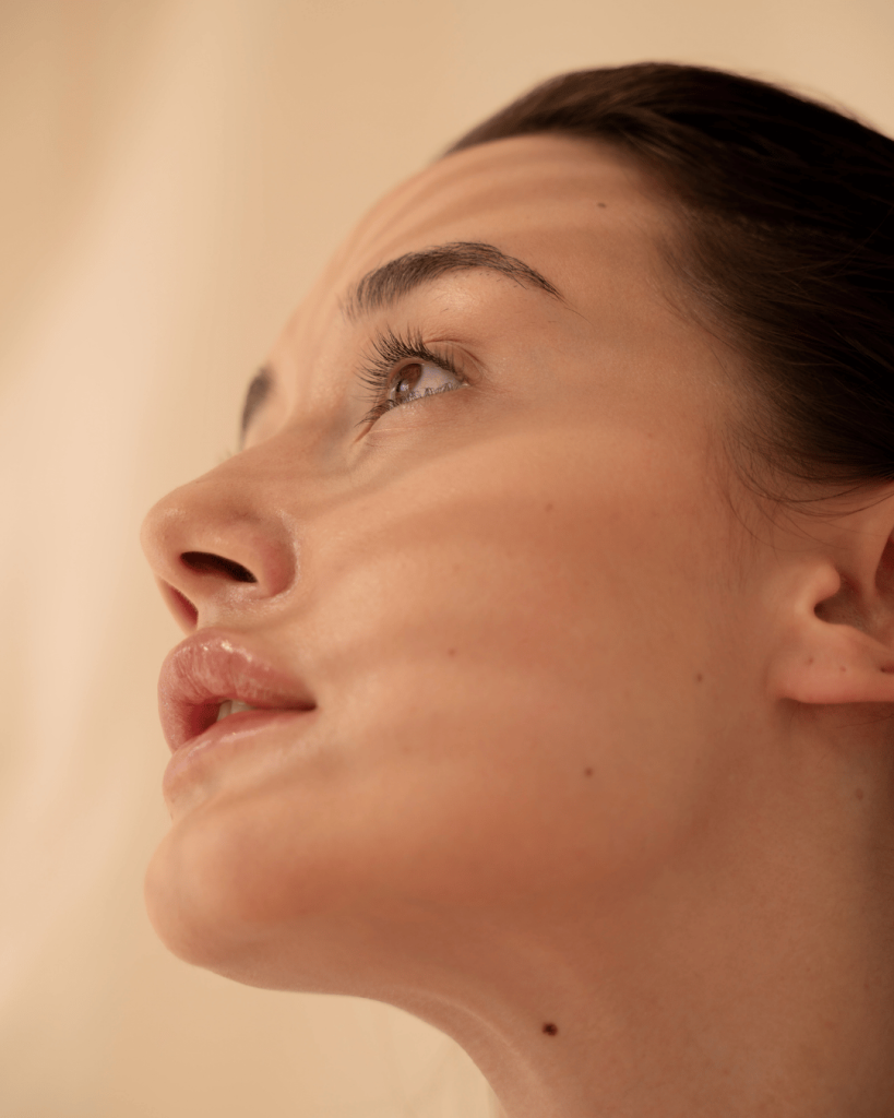 Profile of a woman with glowing skin in warm natural light — a radiant example of modern self-care and skin confidence.