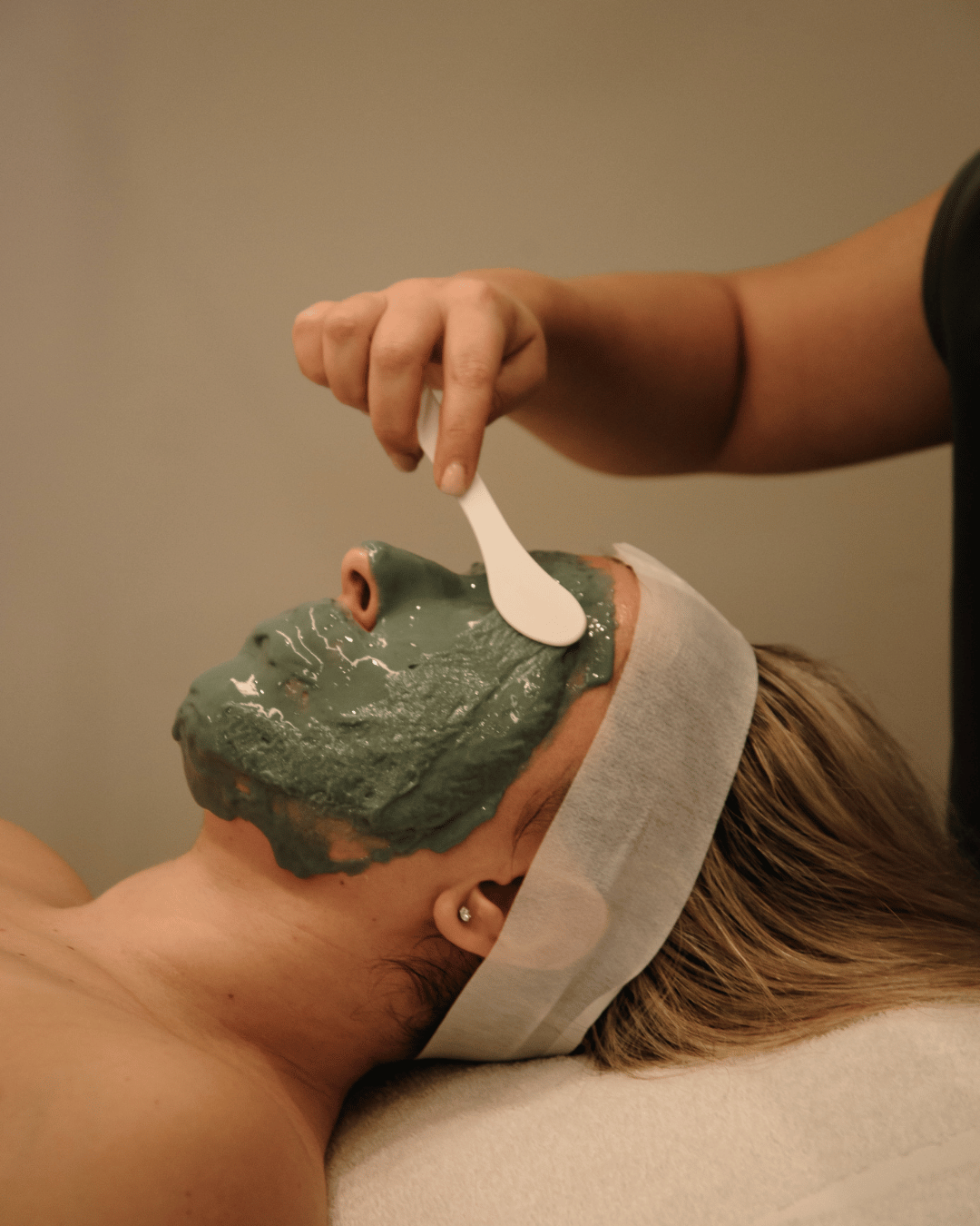 Esthetician applying a green facial mask — highlighting clean beauty, glowing skin, and customized facial therapy.