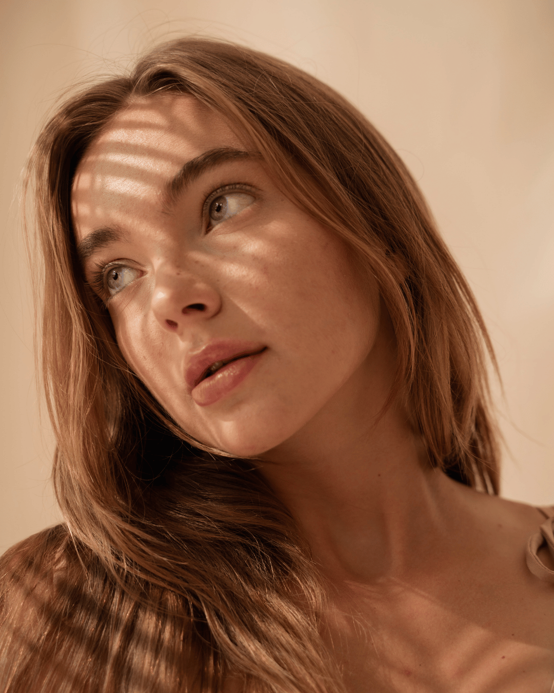 Soft-lit portrait of a woman with glowing skin, gazing in natural light — capturing modern beauty and skin confidence.