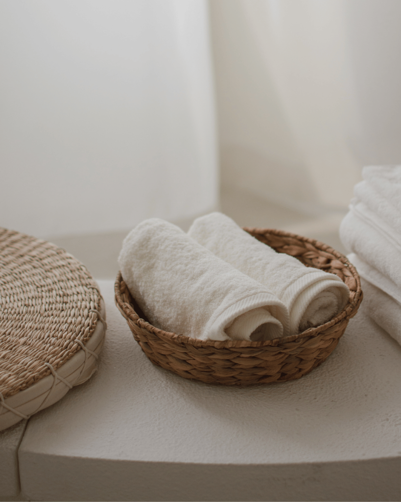Rolled towels neatly arranged in a woven basket — emphasizing modern self-care and serene spa presentation.